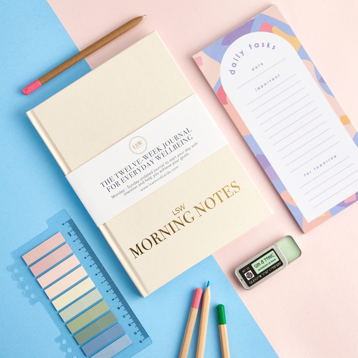 an overhead flat lay shot of stationery items on a pink and blue split background