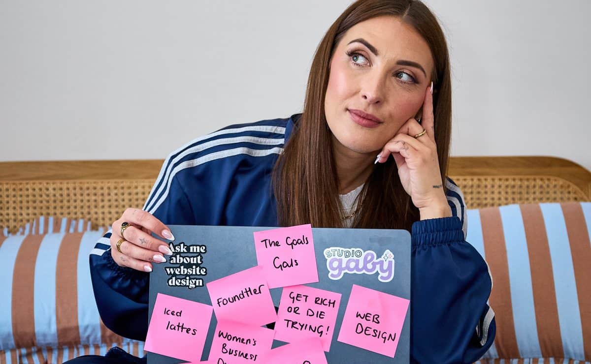 a web designer sat on her bed with her laptop during a branding photoshoot
